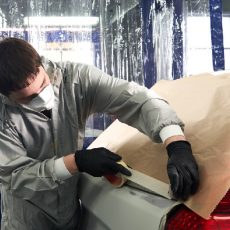 Mechanic covering a car before painting in auto repair service