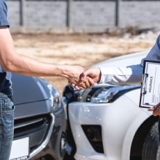 Insurance Agent and customer shaking hands after agreement about in insurance claim, assessed examining car crash, checking and signing on report claim form process after accident collision.